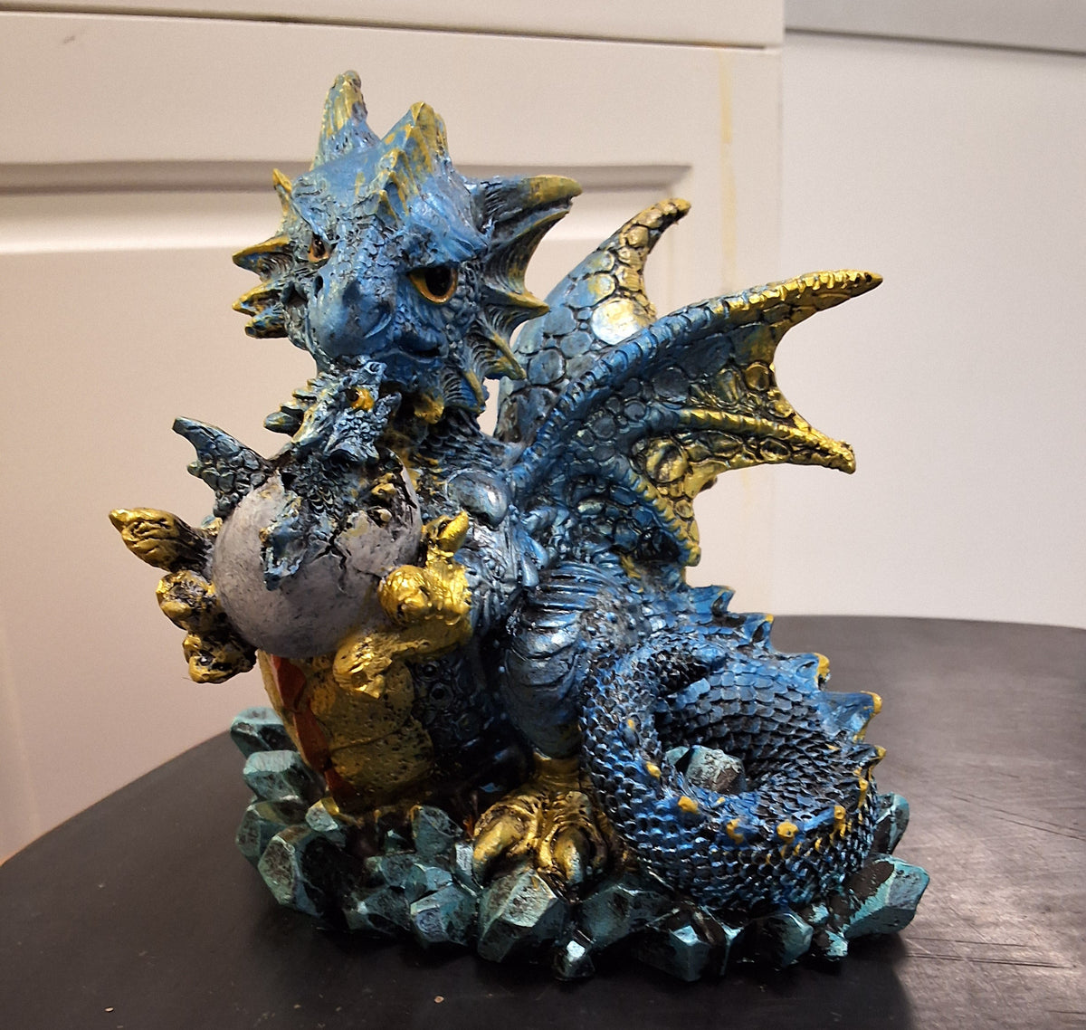 Little blue dragon holding egg with baby inside