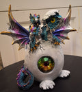 Three pink and blue dragons in egg with gem